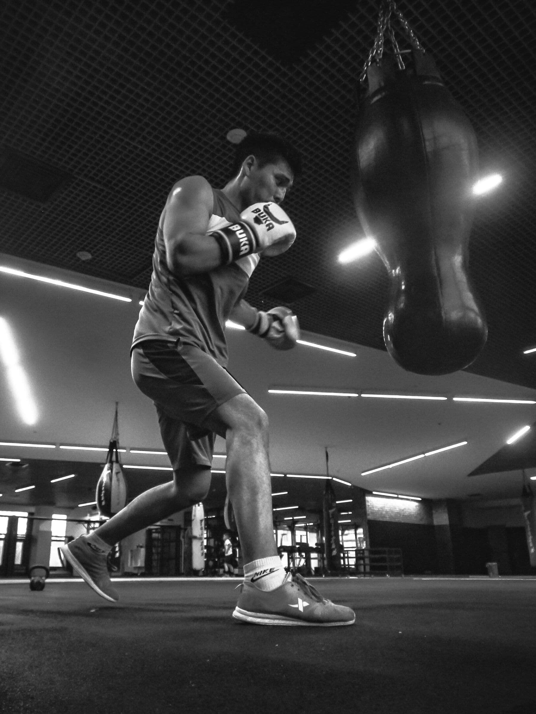 Boxer training on a heavy bag in a dark gym
