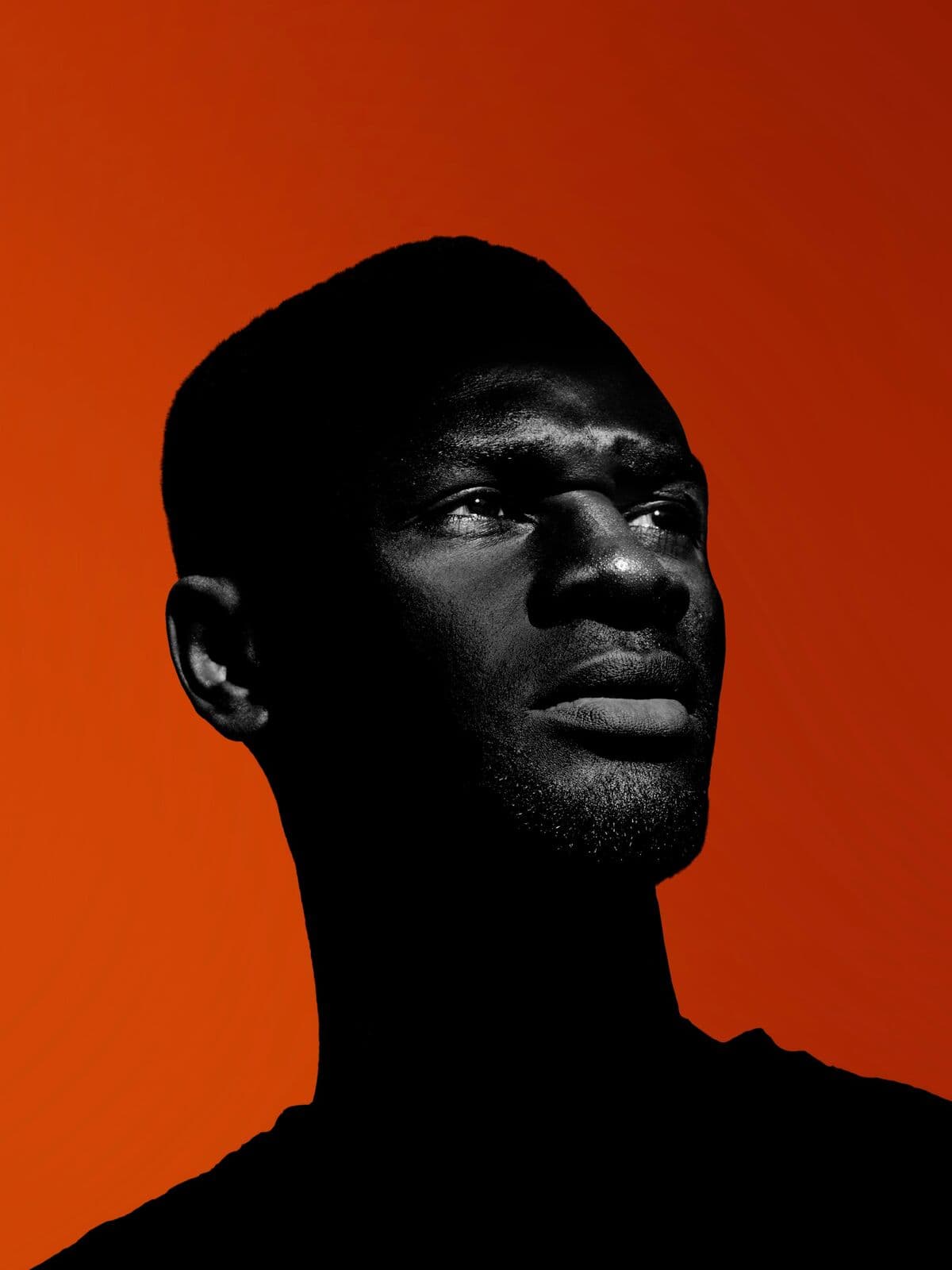 Model in a black top against a bright orange backdrop