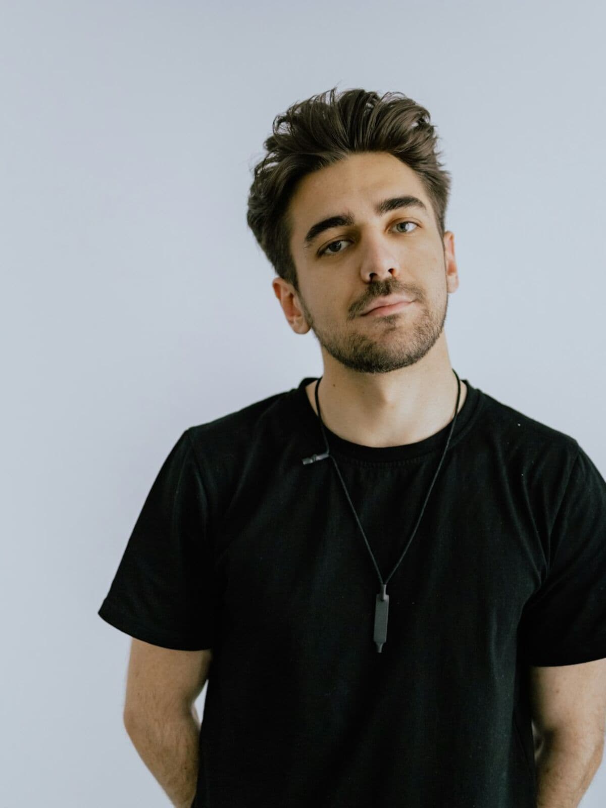 Model in a black crew-neck t-shirt against a pale wall